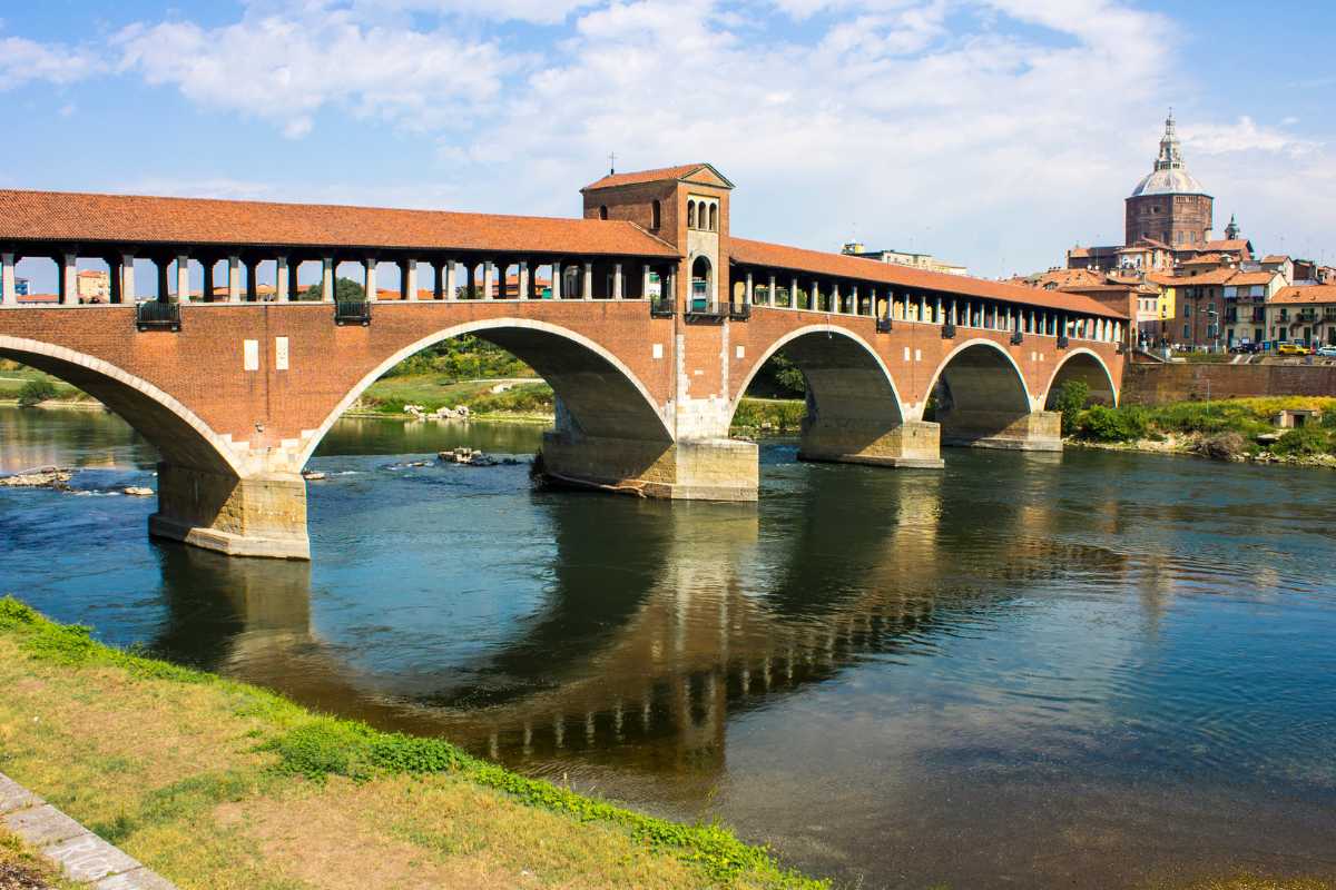 Veduta panoramica di Pavia con la Certosa e il Ponte Coperto, evidenziando l'architettura gotica