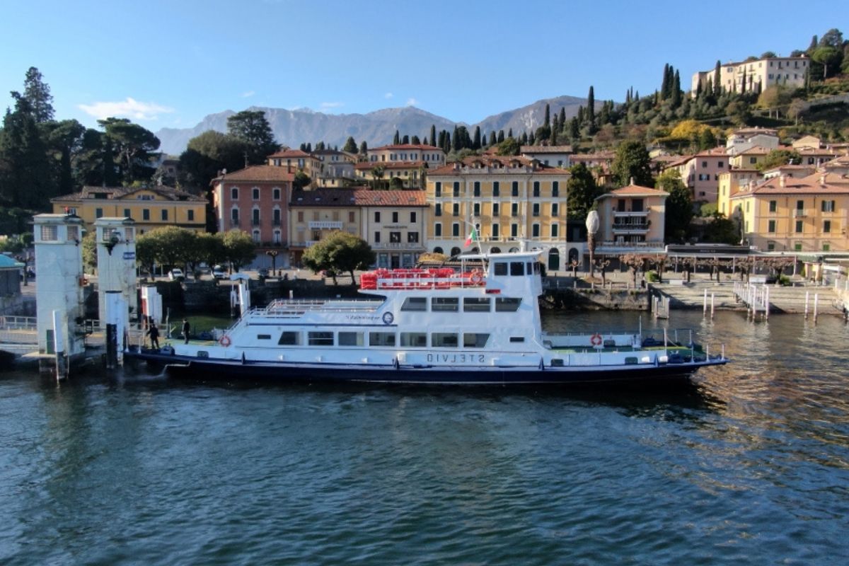 Immagine di un traghetto in navigazione sul Lago di Como, con Lecco in lontananza, catturando la bellezza del viaggio